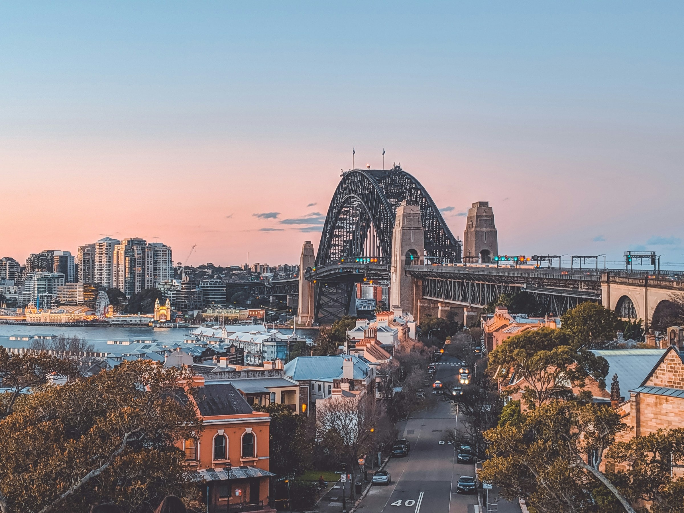 Sydney Harbour Bridge and waterfront buildings in evening light.
